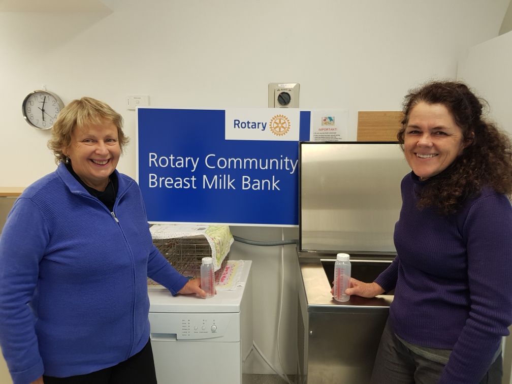 Two Breast Milk Bank volunteers smiling while holding empty milk bottles.